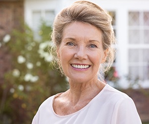 An older woman standing outside and smiling after finding a “dentist near me” in Portland