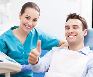 Smiling man in dental chair giving thumbs up