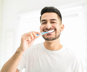 Man preventing dental emergencies in Portland by brushing