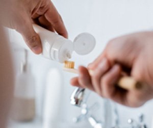 Patient putting toothpaste on toothbrush in bathroom