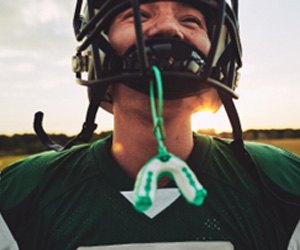 : Green and white mouthguard hanging from football players helmet