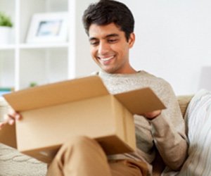 Man smiling while opening package on couch