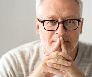 An older man covering his mouth with his hands.