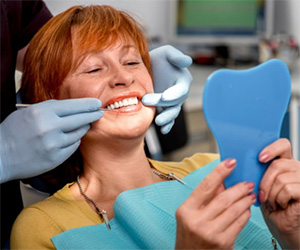 An older woman examining her smile.