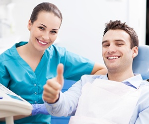 Smiling man in dental chair giving thumbs up