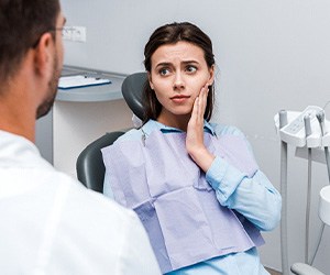 Woman experiencing toothache and talking to dentist