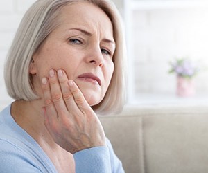 a woman holding her jaw due to tooth pain