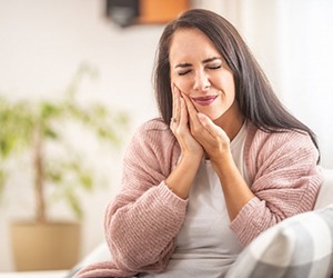 a woman touching her cheek due to tooth pain