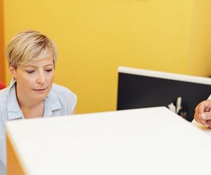 woman sitting at computer in dental office, helping patient