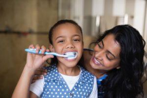 a parent smiling at their child while they brush their teeth