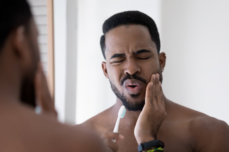 A man holding his jaw due to a delayed root canal